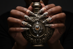 Dark-skin hands wearing steampunk 3D eyeball reusable press-on nails holding dark bronze-gold antique perfume bottle — LuxepressCo