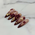 Close-up burgundy gold foil 3D floral reusable salon-quality nails marble background — LuxepressCo