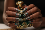 Dark-skin hands wearing Art Nouveau teal chrome reusable press-on nails holding dark green gold ornate perfume bottle — LuxepressCo