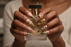 Dark-skin hands wearing cherub angel green chrome gold heart custom press-on nails holding perfume — LuxepressCo
