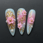 Macro close-up 3D pink floral gold filigree pearl stiletto custom press-on nails dramatic lighting — LuxepressCo
