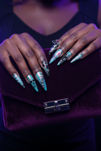 Dark skin hands with teal iridescent skull leopard salon-quality press-on nails holding velvet clutch — LuxepressCo
