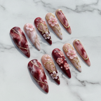 Hero studio shot full set 10 burgundy marble stiletto custom press-on nails white marble background — LuxepressCo