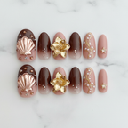 Chocolate brown rose gold chrome 3D magnolia fan shell gold vine star charm custom press-on nails flat lay overhead marble — LuxepressCo