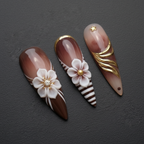 Macro close-up 3D white flower gold foil swirl brown ombre stiletto custom press-on nails dramatic lighting — LuxepressCo