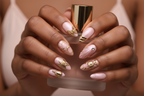 Dark skin hands holding blush pink perfume wearing aurora bloom custom press-on nails gold chrome butterfly — LuxepressCo