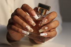 Dark-skin hands wearing ocean shell starfish marble gold bow pearl custom press-on nails holding perfume — LuxepressCo