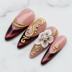 Macro close-up gold swirl filigree burgundy almond press-on nails texture gloss salon-quality nails — LuxepressCo