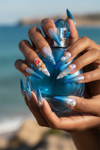 Dark-skin hands holding iridescent blue perfume wearing deep ocean glitter jelly pearl reusable press-on nails — LuxepressCo