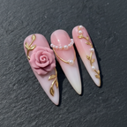 Macro close-up 3D pink rose pearl chain gold vine stiletto custom press-on nails dark background — LuxepressCo