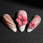 Close-up macro 3D pink flower embellishment pearl chain gold bead custom press-on nails dramatic lighting — LuxepressCo