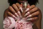 Lifestyle dark skin hands wearing rose gold ribbon pearl custom press-on nails holding blush peonies — LuxepressCo