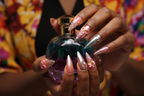 Dark-skin hands wearing chameleon chrome reusable press-on nails holding colorful perfume bottle — LuxepressCo