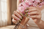 Lifestyle light skin hands wearing gold armor blossom custom press-on nails holding pink cherry blossoms — LuxepressCo