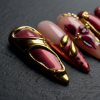 Macro close-up burgundy chrome 3D gold liquid metal swirl custom press-on nails dramatic lighting — LuxepressCo