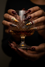 Dark skin hands with wine red amber leopard salon-quality press-on nails holding cognac glass — LuxepressCo