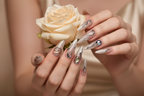 Fair-skin hands wearing nude silver chrome wire custom press-on nails holding champagne silver-dusted rose — LuxepressCo