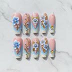 Flat lay top-down 10 blue floral pearl gold vine custom press-on nails white marble — LuxepressCo