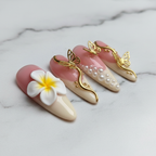 Macro close-up pink cream French tip gold swirl pearl almond custom press-on nails marble background — LuxepressCo