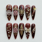 Flat lay top-down full set 10 burgundy royal charm gold crown butterfly filigree pearl rhinestone stiletto press-on nails studio light — LuxepressCo