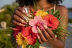 Dark-skin European hands wearing 3D tropical floral butterfly custom press-on nails holding hibiscus bouquet — inclusive reusable nails lifestyle — LuxepressCo