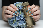 Lifestyle light skin hands wearing teal blue peach ombre galaxy custom press-on nails holding blue hydrangeas — LuxepressCo