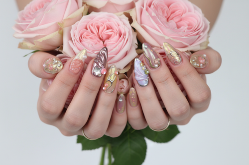 Fair-skin hands wearing aurora holographic custom press-on nails holding pink rose bouquet — LuxepressCo