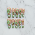 Flat lay top-down 10 sage green 3D floral custom press-on nails arranged neatly white marble studio — LuxepressCo