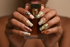 Dark skin hands holding amber perfume wearing baroque gold vine gemstone custom press-on nails — LuxepressCo