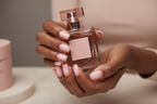 Dark skin hands holding blush perfume wearing pink marble web custom press-on nails inclusive beauty — LuxepressCo