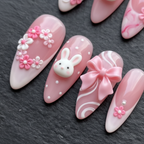 Close-up macro 3D white bunny charm pink bow ribbon baby pink custom press-on nails dramatic lighting — LuxepressCo