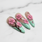 Macro close-up cherry blossom press-on nails glossy texture mint green marble background — LuxepressCo