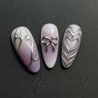 Macro close-up 3D chrome bow and heart almond press-on nails lavender purple ombre dramatic lighting custom press-on nails — LuxepressCo