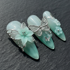 Close-up macro silver filigree butterfly charm 3D translucent mint flower aurora shimmer custom press-on nails dramatic — LuxepressCo