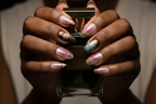 Dark skin hands holding gold perfume wearing gold chrome aurora custom press-on nails inclusive beauty — LuxepressCo
