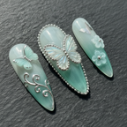 Macro close-up 3D silver chrome butterfly mint green custom press-on nails dramatic lighting — LuxepressCo