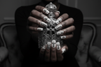 Dark-skin hands wearing gothic silver chrome reusable press-on nails holding silver gothic cross perfume bottle — LuxepressCo