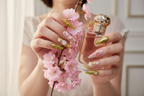 Lifestyle light skin hands wearing gold butterfly garden custom press-on nails holding cherry blossoms — LuxepressCo