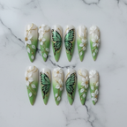 Flat lay top-down full set 10 green butterfly floral stiletto custom press-on nails marble — LuxepressCo