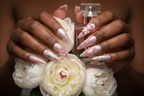 Lifestyle dark skin hands wearing pink fortune angel wing custom press-on nails holding white peonies — LuxepressCo