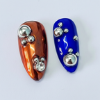 Macro close-up burnt orange and cobalt blue chrome salon-quality press-on nails rhinestone ball beads — LuxepressCo