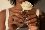 Dark-skin European hands wearing tortoiseshell amber 3D swirl custom press-on nails holding white rose — inclusive reusable nails lifestyle — LuxepressCo