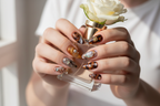 Light-skin European hands wearing tortoiseshell amber 3D swirl custom press-on nails holding white rose — salon-quality nails lifestyle — LuxepressCo