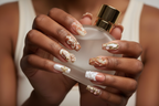 Dark skin hands holding pearl white perfume wearing ocean pearl custom press-on nails terracotta blush — LuxepressCo