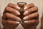 Dark skin hands holding gold perfume wearing celestial gold heart star moon custom press-on nails nude aurora — LuxepressCo